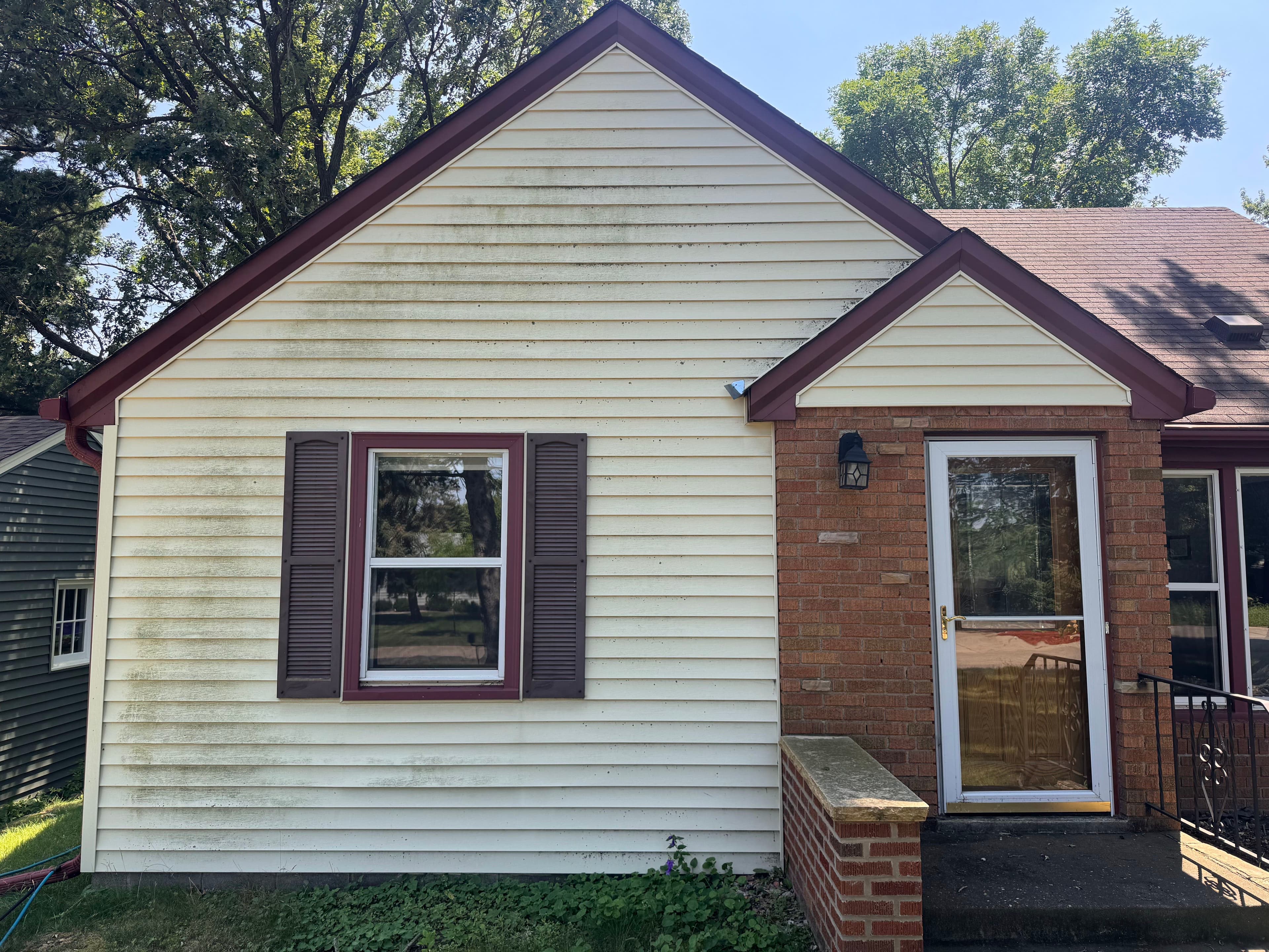 Exterior view of a house featuring a tan facade, maroon trim, and a welcoming front porch.