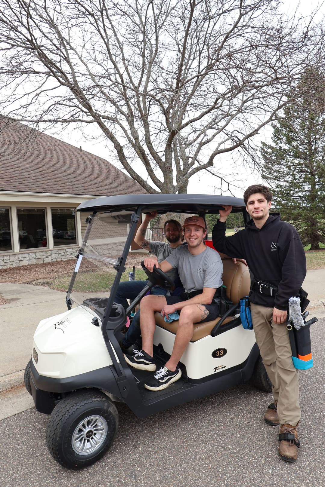 Young men on a golf cart outside a building, smiling and enjoying a casual day.