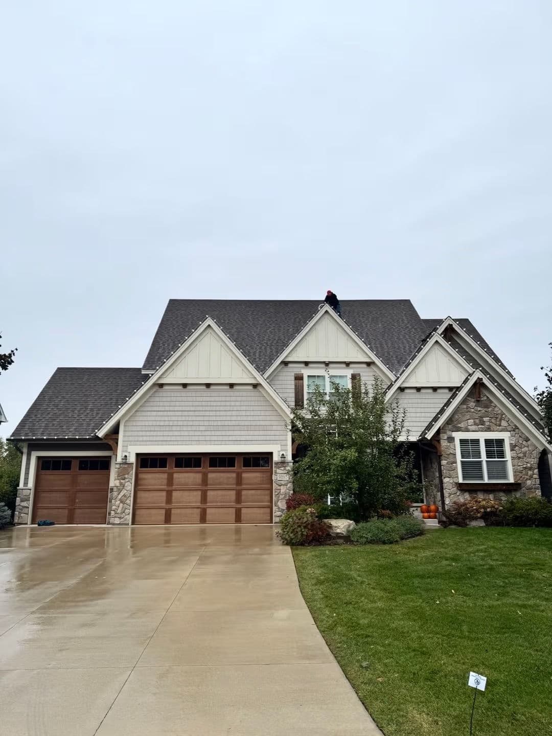Modern two-story home with stone and wood accents, surrounded by green landscaping.