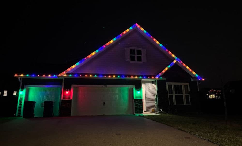 House adorned with colorful Christmas lights in a festive winter night setting.