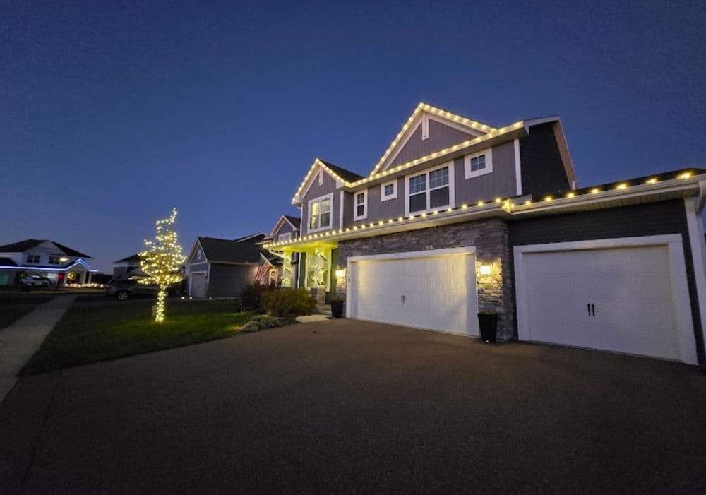 Modern house with exterior holiday lights, cozy evening ambiance, and landscaped yard.