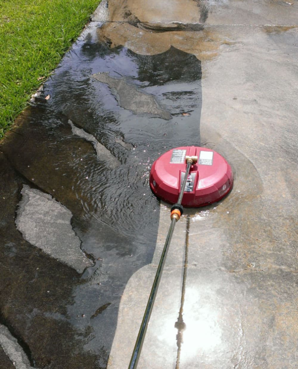 Surface cleaner on a wet driveway, cleaning grime and stains from concrete.