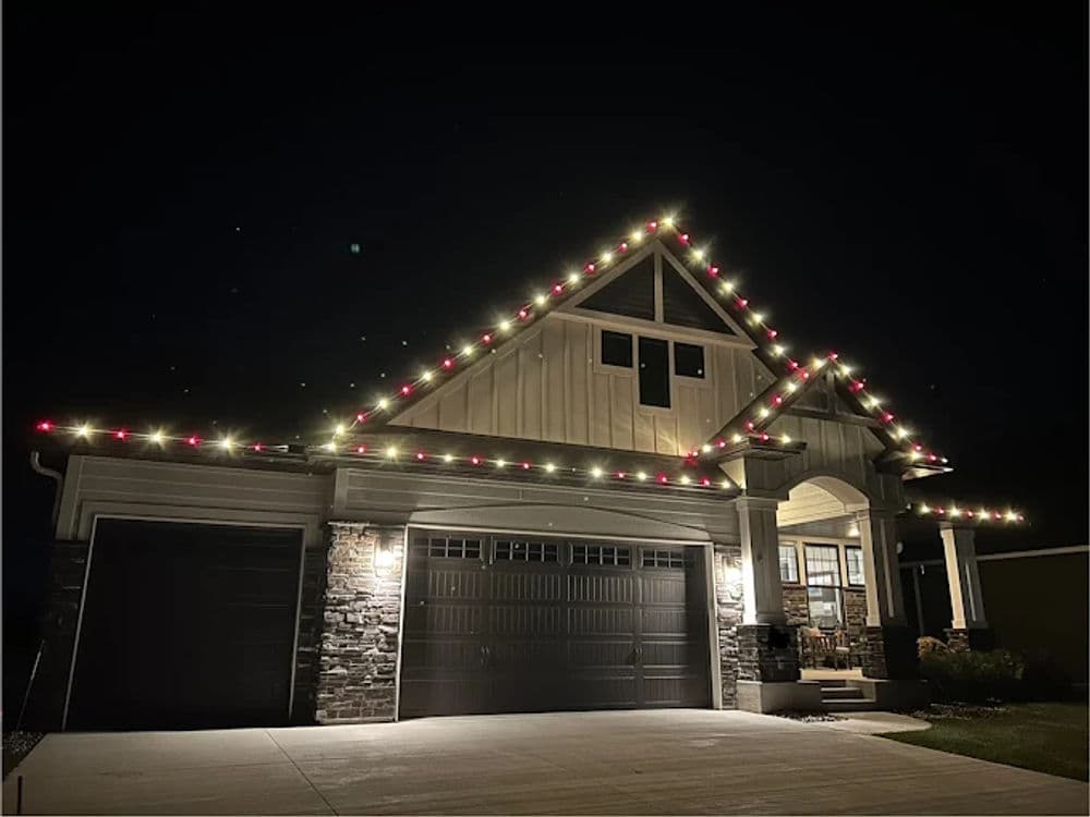 House decorated with festive string lights along the roof, showcasing holiday spirit at night.