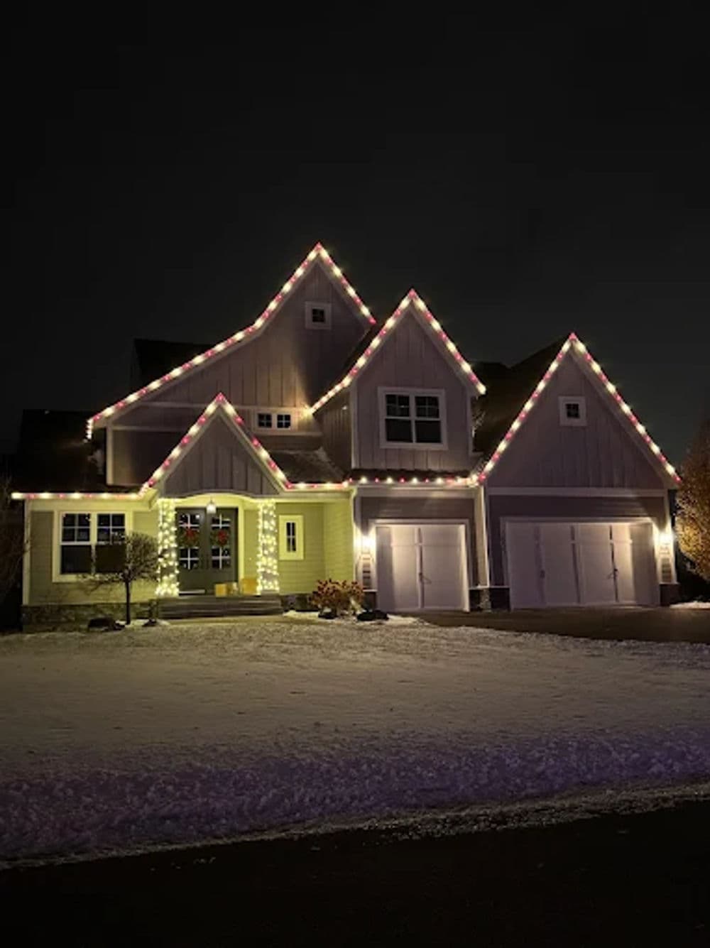Cozy winter home adorned with colorful holiday lights against a dark night sky.